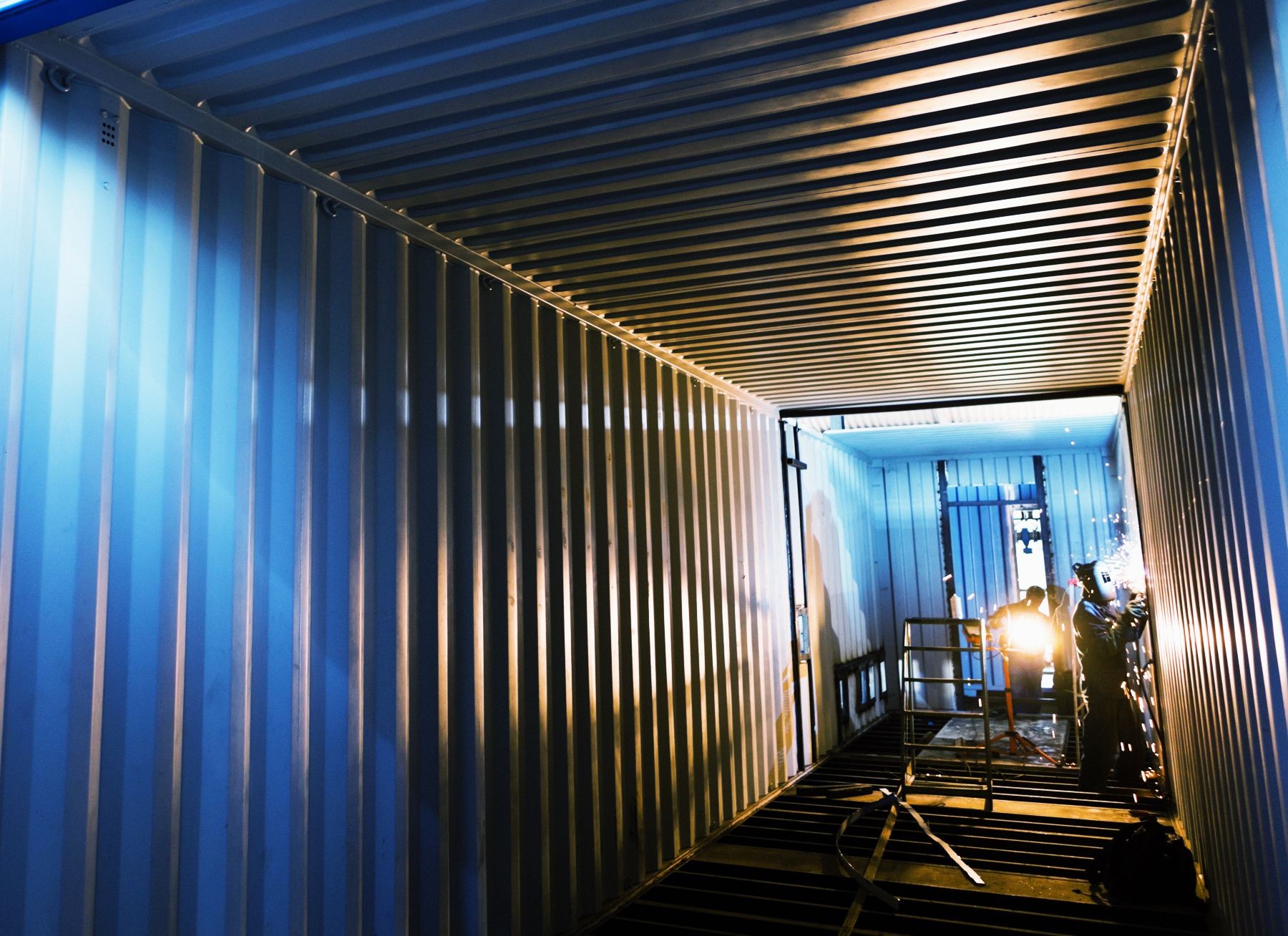 Welders working inside empty cargo container